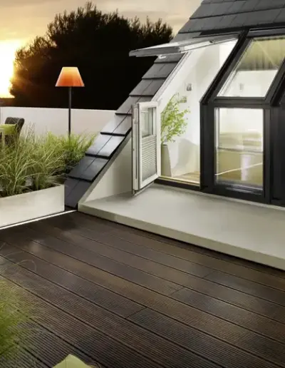 Bodentiefe Fenster mit Zugang zur Dachterrasse im Abendlicht.