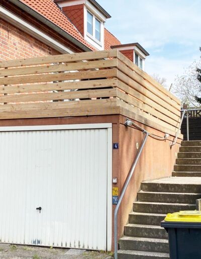 Holzsichtschutz um eine erhöhte Terrasse über einer Garage.