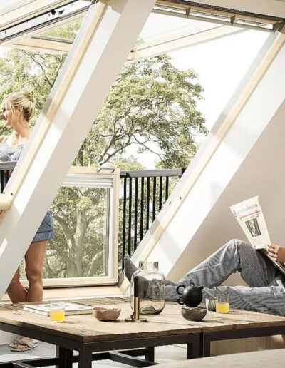 Geöffnetes Dachfenster mit ausklappbarem Balkon in einem Wohnraum.